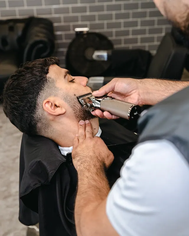 Close-up of a beard being shaped with clippers