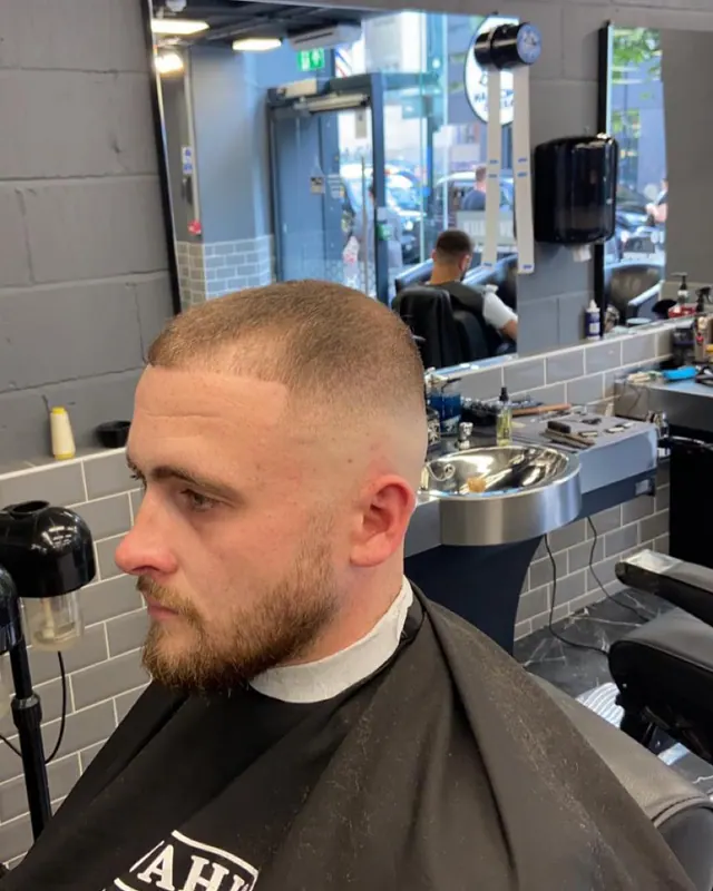 A buzz cut with a full beard, in the chair