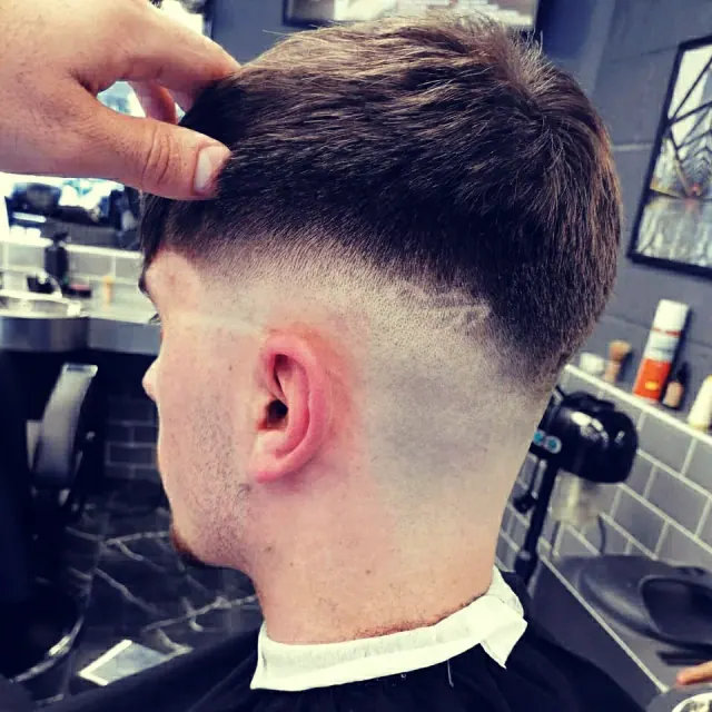 A skin fade behind the ear, the top held up