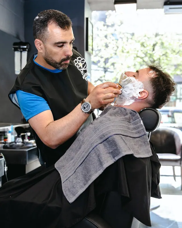 A hot towel shave in progress, the client lathered and reclined