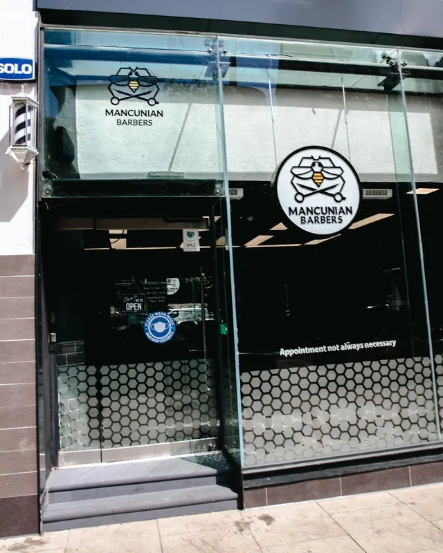 The shopfront at 111b Piccadilly, with the Mancunian Barbers logo on the glass