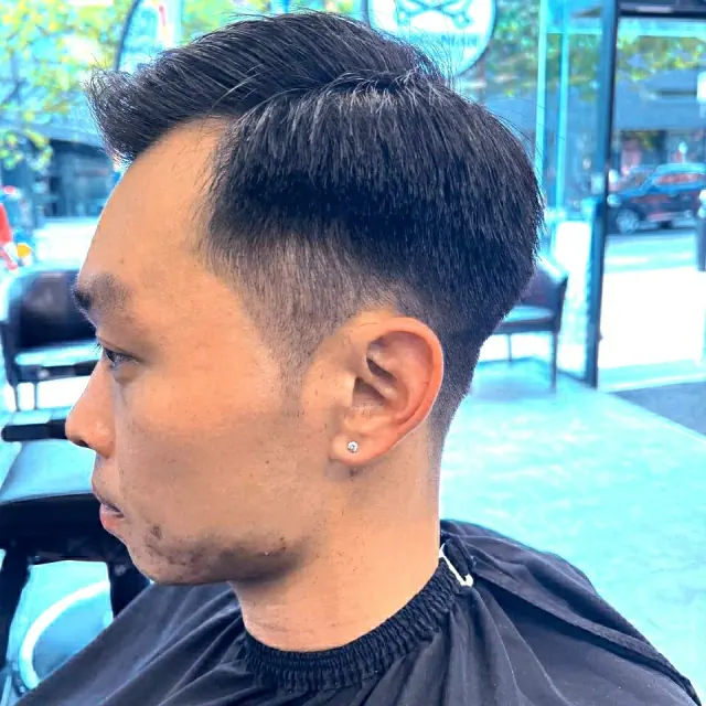 A side-parted cut with a taper, side view