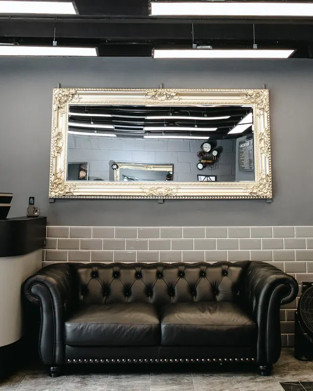A Chesterfield sofa under a gilt-framed mirror